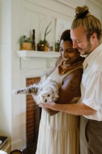 A mixed race couple that is smiling and holding their cat. Represents the needs for couples counseling to help build a healthy relationship in Katy, TX 77494
