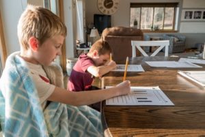 Two young boys sitting at the table doing homework. Represents the need for family counseling to help parenting children with ADHD in Katy, TX 77494